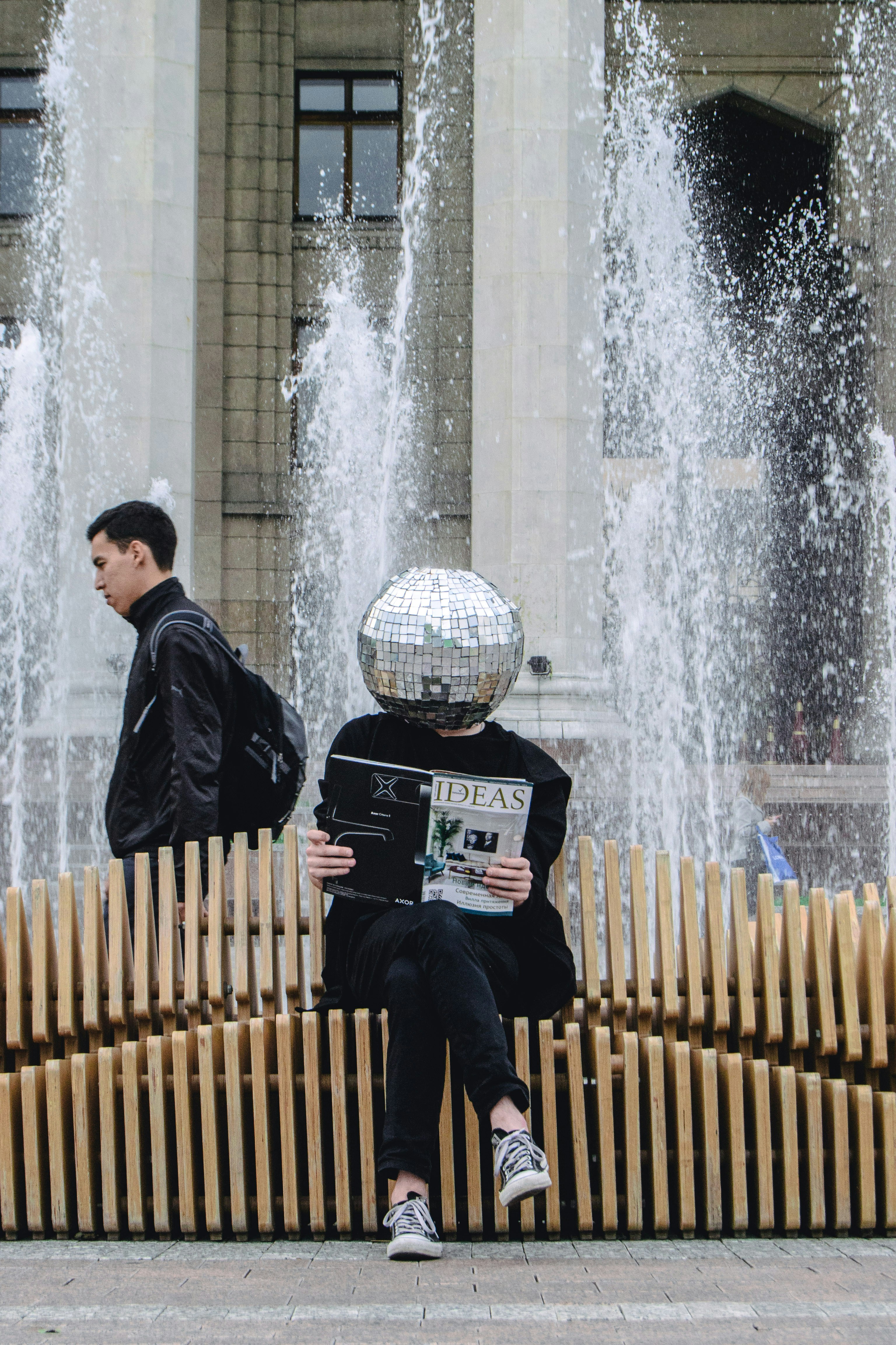 Person with a disco ball head reading a magazine