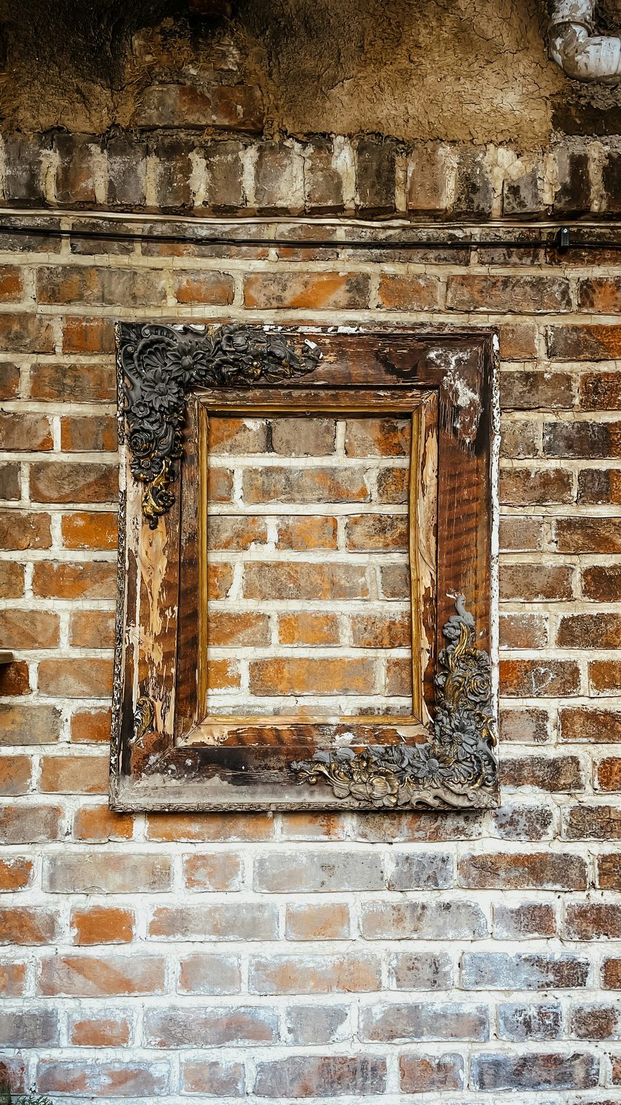 Empty ornate frame against exposed brick wall