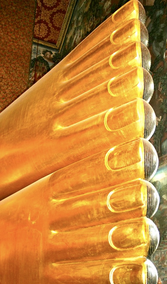 Abstract close-up of rows of glowing golden sculpted forms against an ornate painted wall